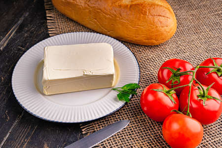 Fresh tasty butter on a kitchen table. A piece of butter on a white plate.の写真素材