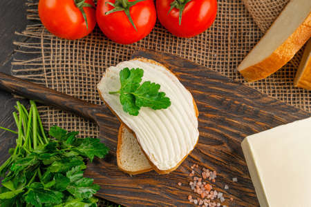 Tasty bread with butter on wooden cutting board. A large piece of butter.の写真素材