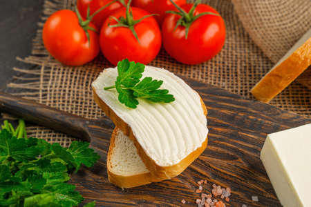 Tasty bread with butter on wooden cutting board. A large piece of butter.の写真素材