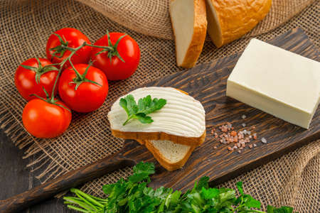 Tasty bread with butter on wooden cutting board. A large piece of butter.の写真素材