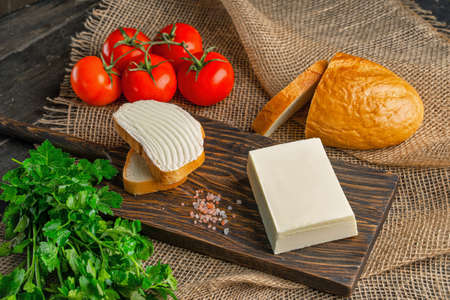 Tasty bread with butter on wooden cutting board. A large piece of butter.の写真素材