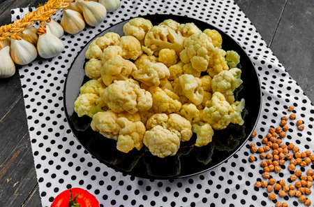 Cauliflower on a black plate. Vegetables on the kitchen table.の写真素材