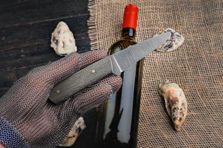Hand with oyster knife in protective gloves. Close up.の写真素材