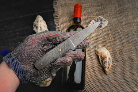 Hand with oyster knife in protective gloves. Close up.の写真素材