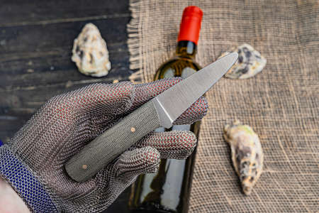 Hand with oyster knife in protective gloves. Close up.の写真素材