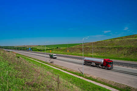 Asphalt road in a rural landscape. Trucks on the road.の写真素材