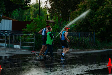 Kazan, Russia. August 22, 2021. A man pours water on athletes at a triathlonのeditorial素材