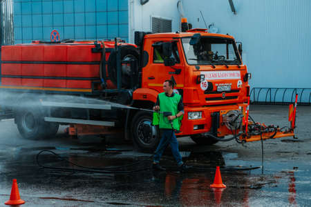 Kazan, Russia. August 22, 2021. A man pours the road. Dust removal, protection of the environment.のeditorial素材