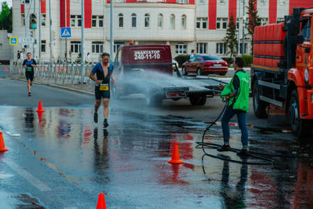 Kazan, Russia. August 22, 2021. A man pours water on athletes at a triathlonのeditorial素材