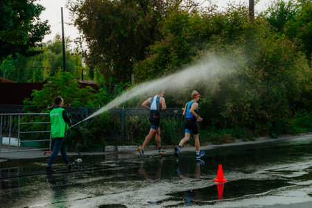 Kazan, Russia. August 22, 2021. A man pours water on athletes at a triathlonのeditorial素材