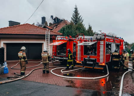 Fire trucks are standing by the burning house. Fighting the fire. Firefighters are extinguishing an open fire. Kazan, Russia. 02 November 2021.のeditorial素材