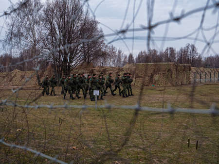 Soldiers of the Russian army walking across a field. View through barbed wire.のeditorial素材