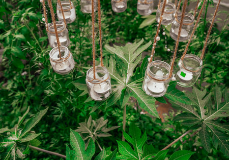 Hanging candles in the greenhouse. Hanging decorative lights. Candles in a glass in the gardenの写真素材