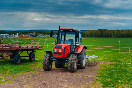 Red tractor in a rural landscape. Hay harvesting in the field by means of a tractorの写真素材