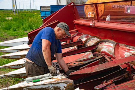 Kazan, Russia. 2022, June 12. A man fixing a combine harvester. Modern agricultural machinery.