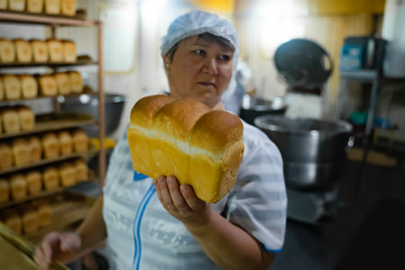 A bakery worker demonstrates a freshly baked loaf of breadのeditorial素材