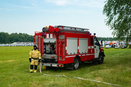 A fireman with a water hose stands near the fire truck. Russian firemen stands near a fire truck during an exerciseのeditorial素材
