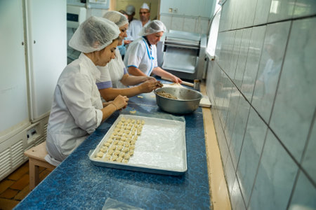Women making Pelmeni or dumplings in a factory.のeditorial素材
