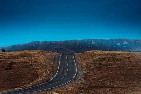 A winding asphalt road in a mountainous area.の写真素材