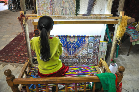 Young woman weaves a carpet on handloom.の写真素材