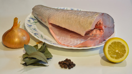 Fish on a plate, onion, pepper, laurel leaf, lemon.の写真素材