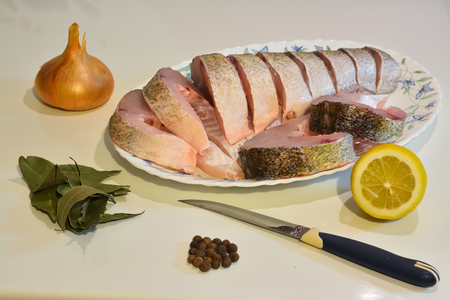 Sliced fish on a plate, knife and spices around.の写真素材
