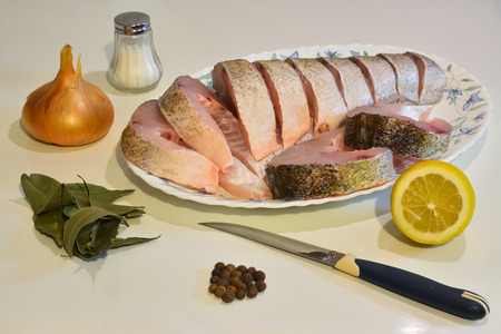 Sliced fish on a plate, knife, salt and spices around.の写真素材