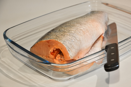 Fish for cooking and knife in a glass tray.の写真素材