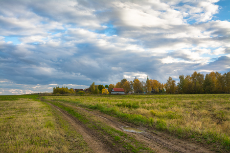 Autumn landscape - road through the meadow to the village.の写真素材