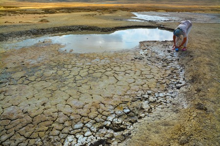 Woman collects healing mud from a mud lake.の写真素材