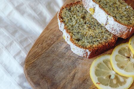 Cake with poppy seeds and lemon zest, sprinkled with powdered sugar. Cupcake with lemon on a wooden boardの写真素材