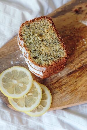Cake with poppy seeds and lemon zest, sprinkled with powdered sugar. Cupcake with lemon on a wooden boardの写真素材