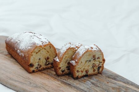 Raisin cake, dusted with icing sugar. Cupcake with raisins on a wooden boardの写真素材