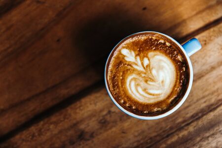 Cappuccino in a blue mug on a wooden table. Coffee view from above.の写真素材
