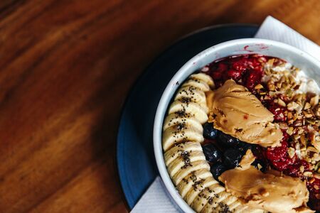 Healthy vegan breakfast with oatmeal bowl with banana, peanut butter, blackberries, raspberries, nuts, seeds and goji berries.の写真素材