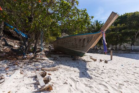 A broken boat stands on the sand. Boat by the sea. Fishing boat washed ashore.の写真素材