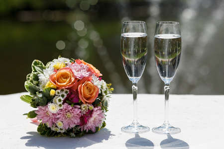 two glasses of sparkling wine and bouquet of the bride.の写真素材