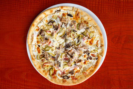 large pizza with meat, cheese, mushrooms on a white plateの写真素材