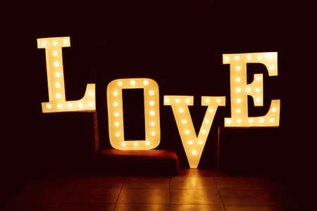 word love from big letters with glowing light bulbs on a dark backgroundの写真素材