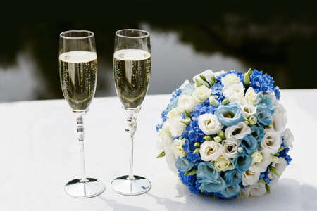 two glasses of champagne and a bouquet of white and blue roses. Soft focus, selective focusの写真素材