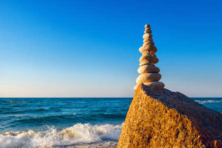Concept of harmony and balance. high pyramid of white stones on the edge of a cliff. Rock Zen at sunsetの写真素材