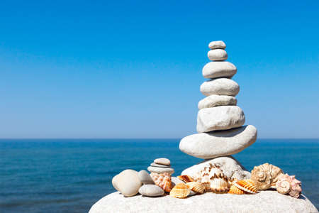 pyramid of white stones and shells on a background of blue sky and seaの写真素材