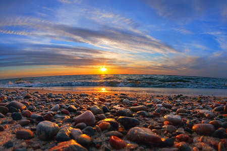 Beautiful sea sunset and sun glare on wet pebblesの写真素材