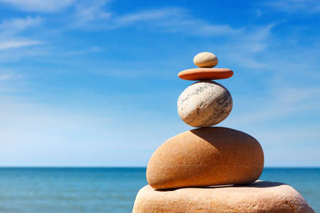 Stones balance on a background of blue sky and sea. Concept of balance and harmony. Rock zenの写真素材