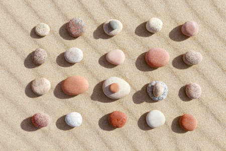Pattern of colored pebbles on clean sand. The concept of peace. Flat lay, top viewの写真素材