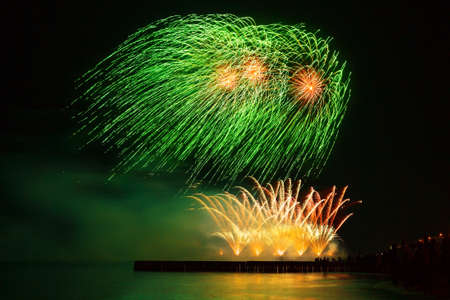 Beautiful, festive fireworks green and golden color over the water with reflection. extremely long...