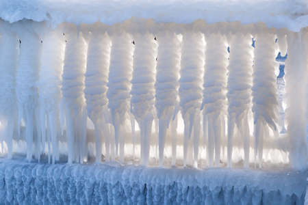 Iced street fencing. Big, long, white icicles. Winter Ice Stormの写真素材