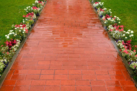 Beautiful pavement of red and brown clinker brick. Walking path decorated with flowersの写真素材