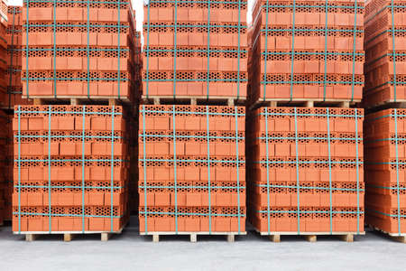 Stacks of new, red ceramic brick stacked on wooden palletsの写真素材