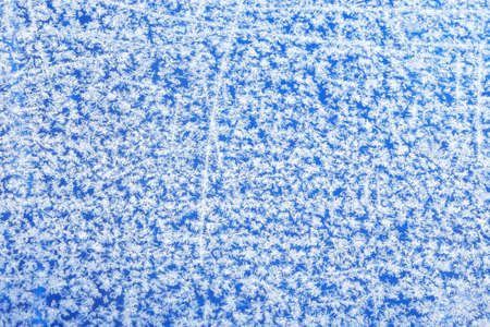 Patterns of natural hoarfrost on glass on a blue background. winter frost background, texture. Soft...